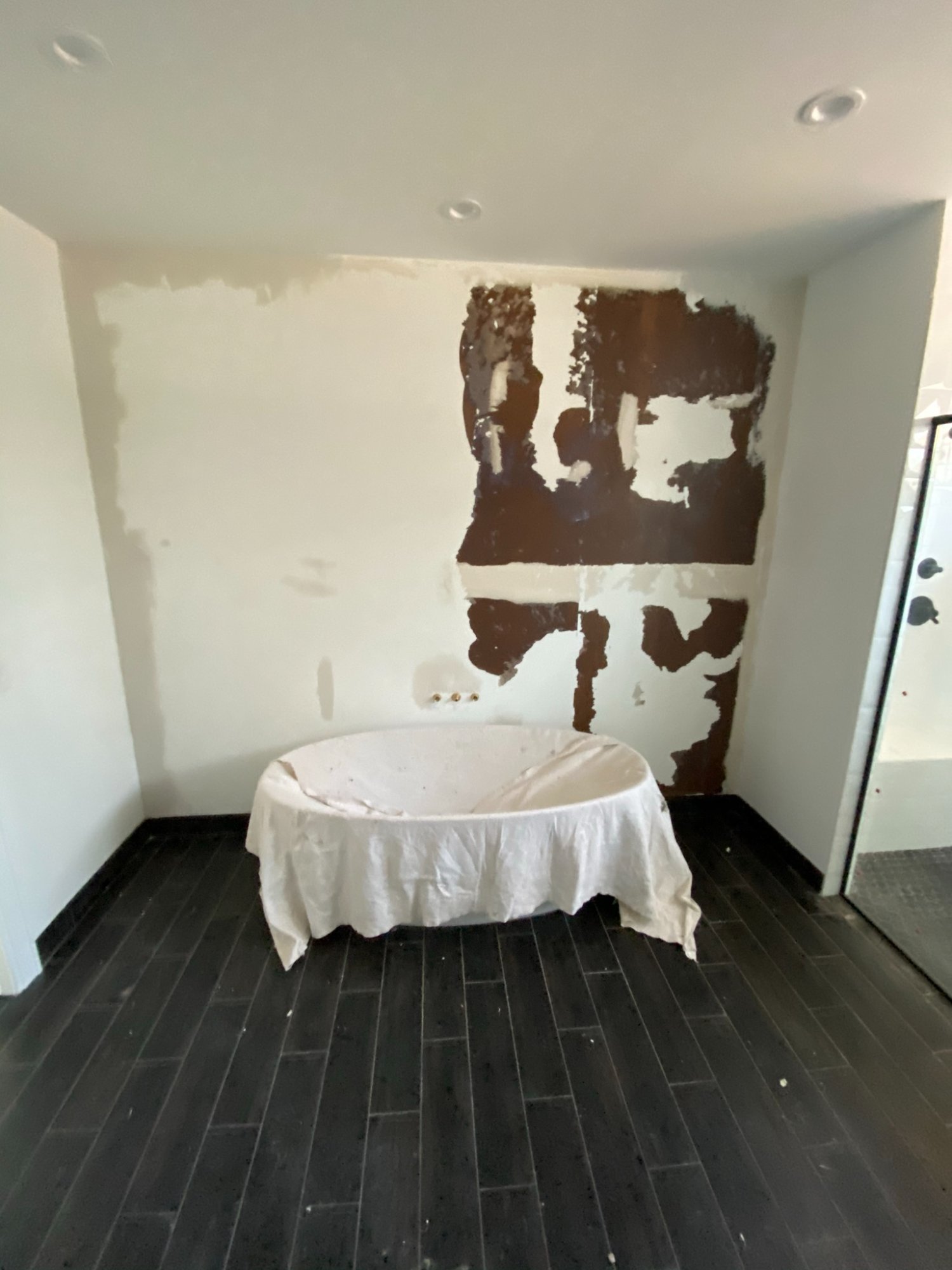 damaged drywall behind bathtub before wallpaper prep