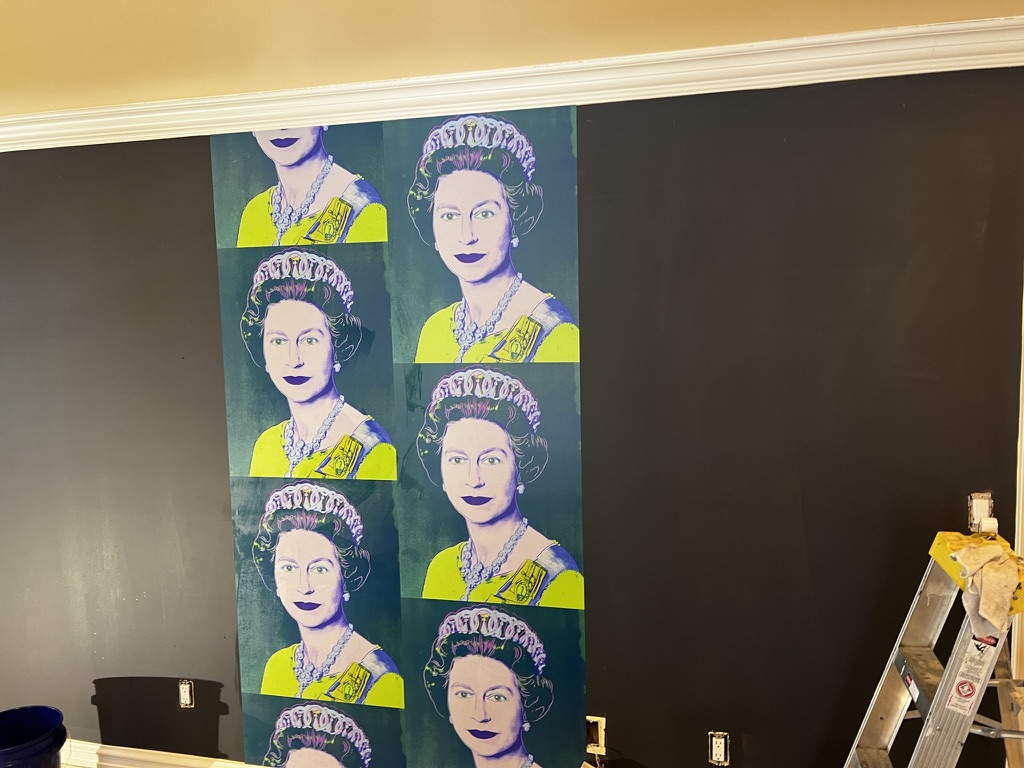 first strip of wallpaper going up on tinted wall