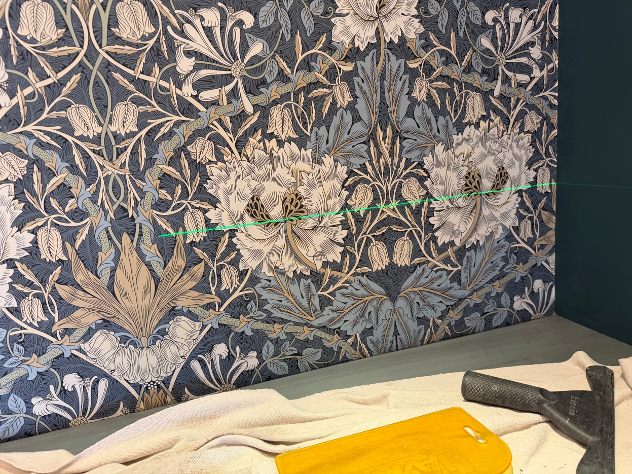 Close-up of Morris & Co. Honeysuckle & Tulip wallpaper showing the mirrored floral repeat in indigo, cream, and gold.