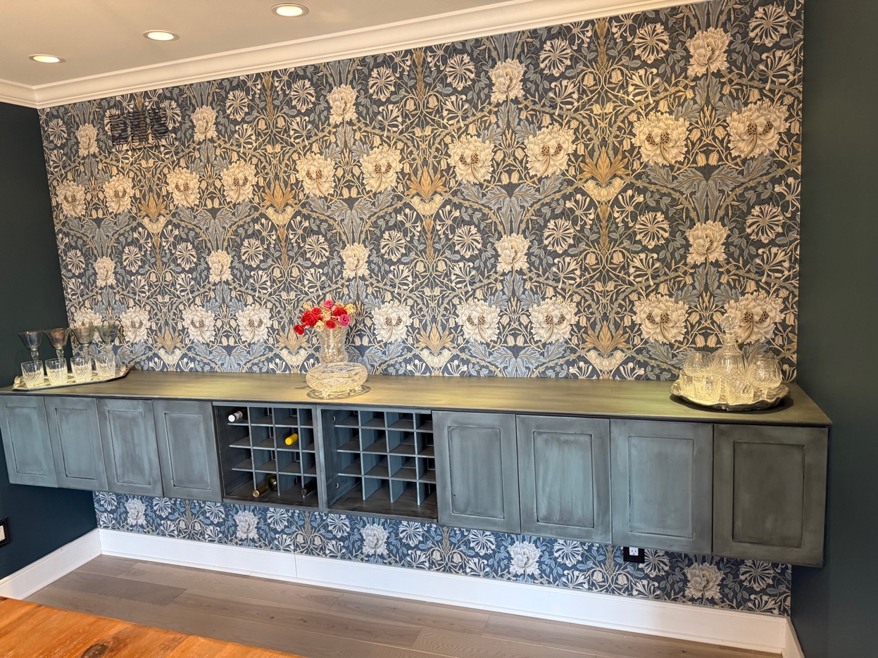 Completed Morris & Co. Honeysuckle & Tulip focal wall over a built-in wine bar, styled with crystal glassware and flowers — Birmingham, MI. Installed by Bernau Designs.