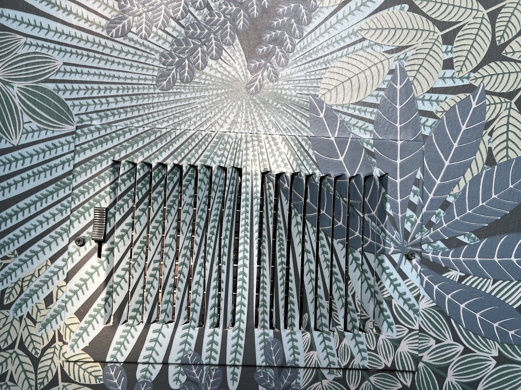 Return-air register cut into Borastapeter Velvet Leaves wallpaper, with the pattern carrying across and the substrate texture visible.