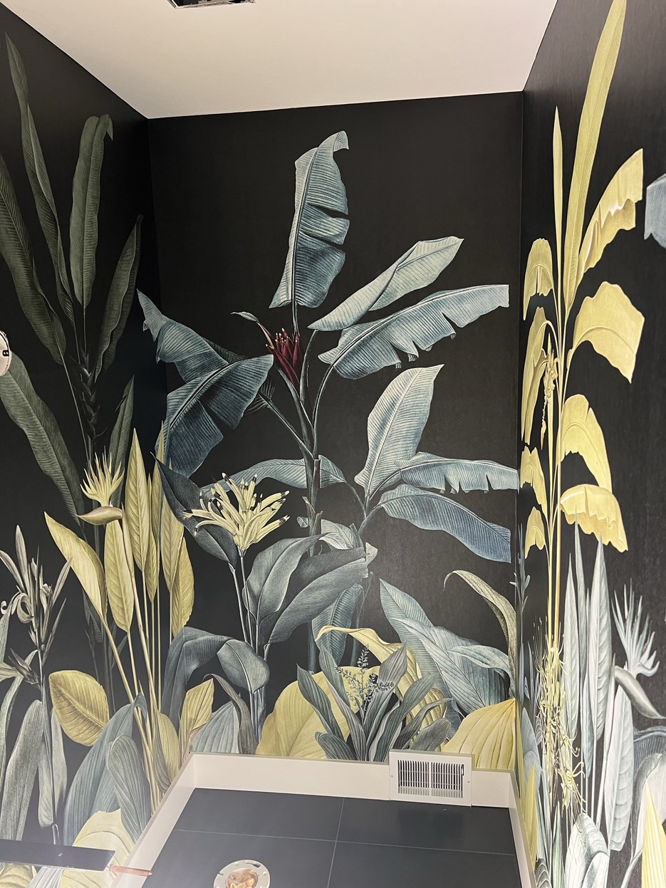 Hovia tropical mural in chartreuse and blue-grey on a black ground, carried around an interior corner in a Michigan installation.