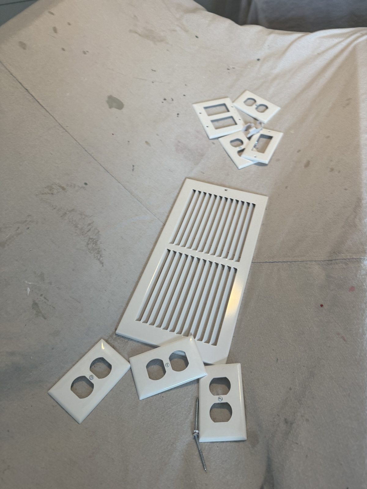 Nursery wall preparation with outlet plates and return-air vent removed before wallpaper installation.