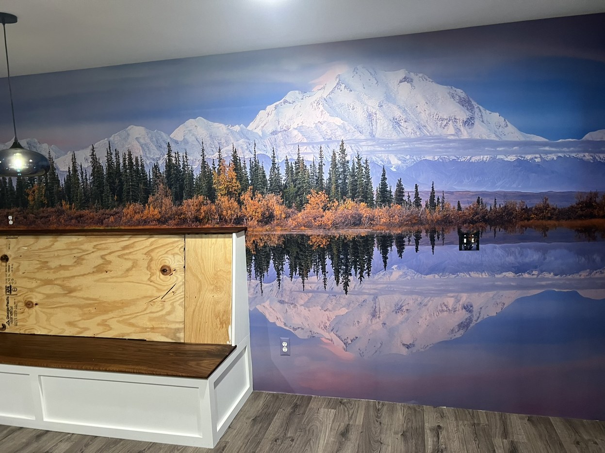 Photowall custom mural of Denali reflected in a lake, sized so the waterline sits just above a built-in banquette in a Michigan dining area.
