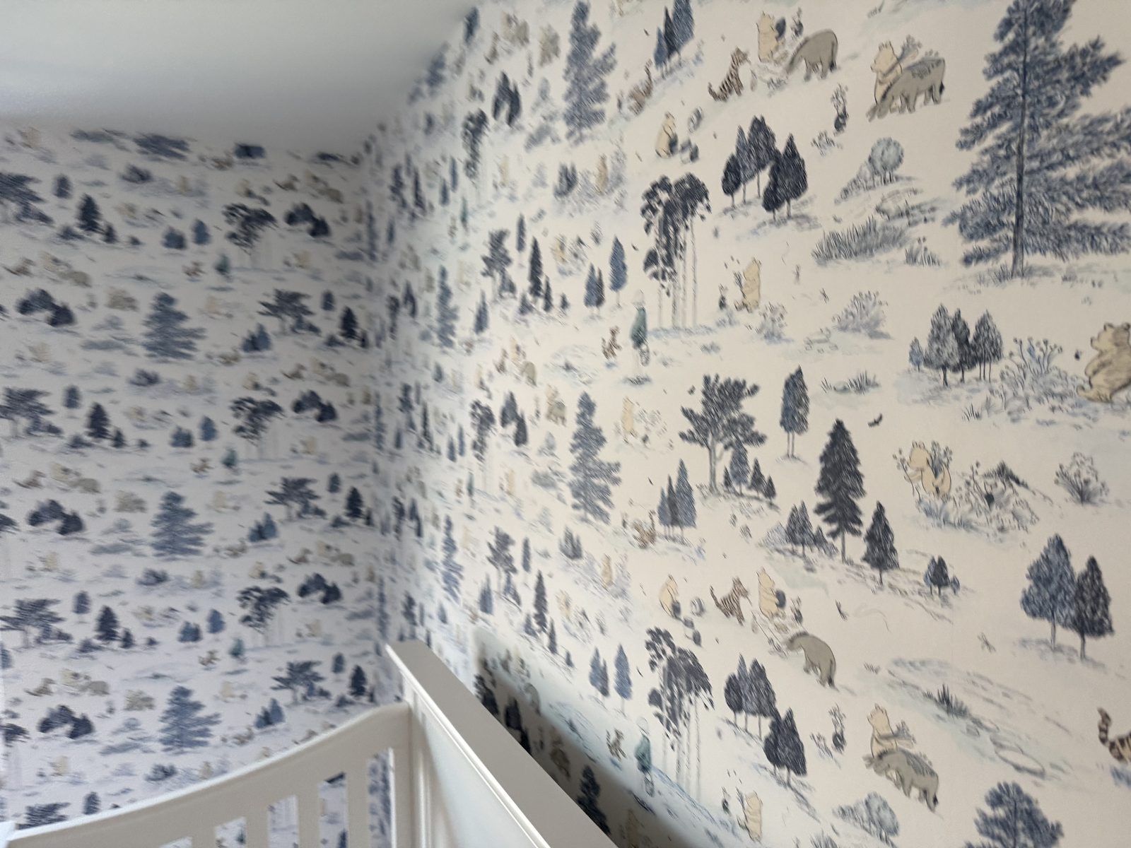 Close-up detail of Sanderson Winnie the Pooh Bonbon Blue wallpaper showing Pooh, Tigger and Christopher Robin among the trees.
