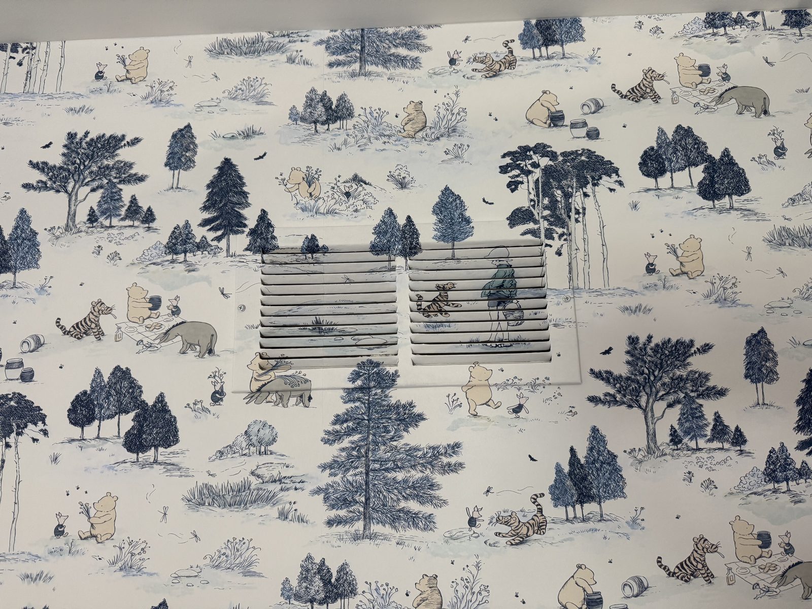 Return-air vent covered in matching Sanderson Winnie the Pooh wallpaper, disappearing into the surrounding pattern.