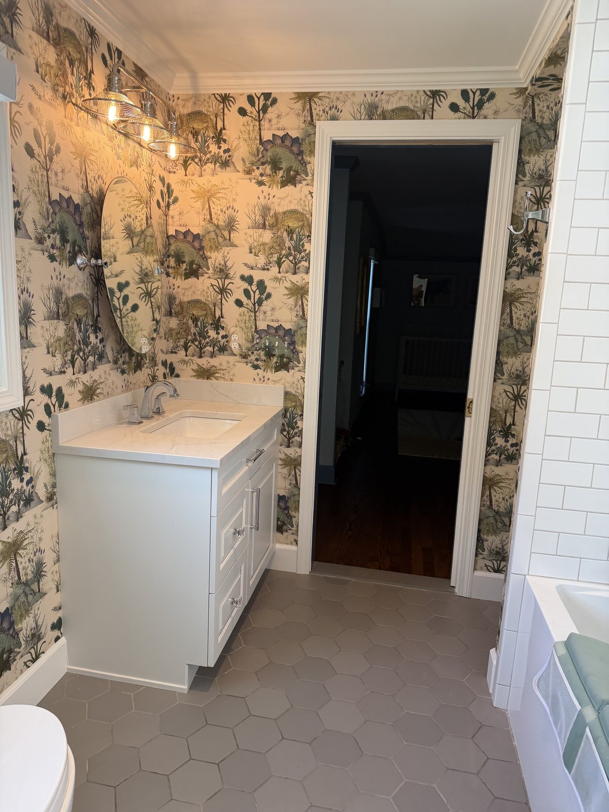 The finished children's bathroom: white vanity, the doorway to the nursery, and the tiled tub alcove at right.