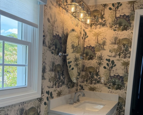 House of Hackney Dinosauria Ecru wallpaper in a kids' bathroom in Birmingham, Michigan, with a white vanity and oval mirror.