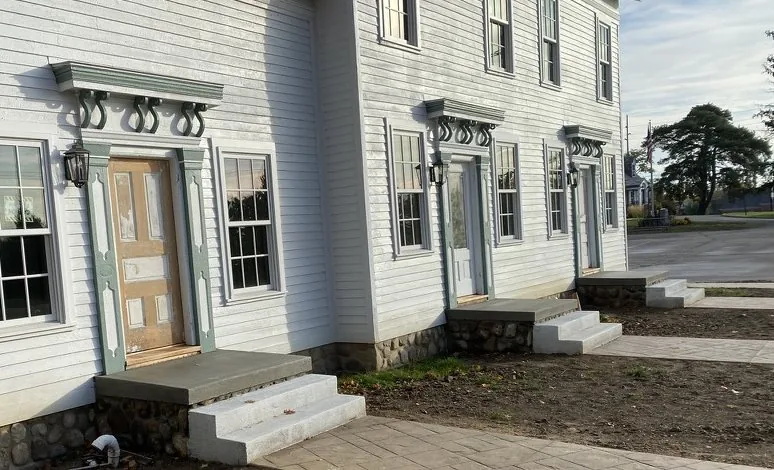 The front elevation of the Niles-Barnard House showing three separate entrances, each with its own bracketed hood and stone-faced stoop.