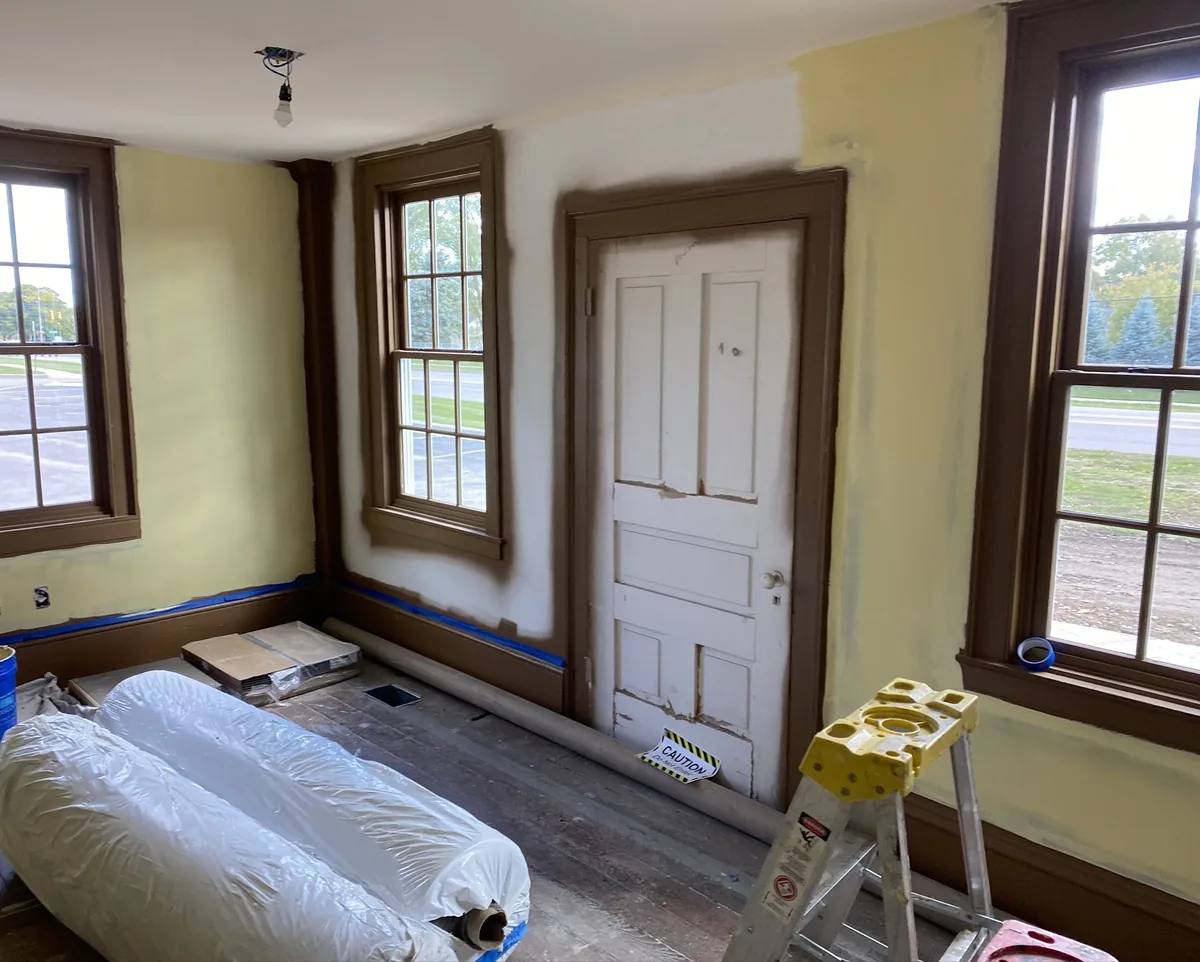 Primer going on the main floor of the Niles-Barnard House, tinted pale yellow to match the wallcovering ground, with blue tape protecting the finished brown trim.